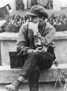 Vertov on a park bench wearing a peaked cap