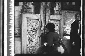 Frau mit Hut küsst das Kreuz